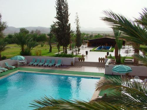 a swimming pool with chairs and umbrellas in a resort at Le Zat in Ouarzazate
