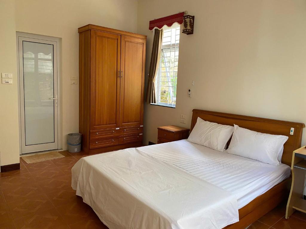 a bedroom with a large bed with white sheets at Jackfruit Homestay in Ha Long