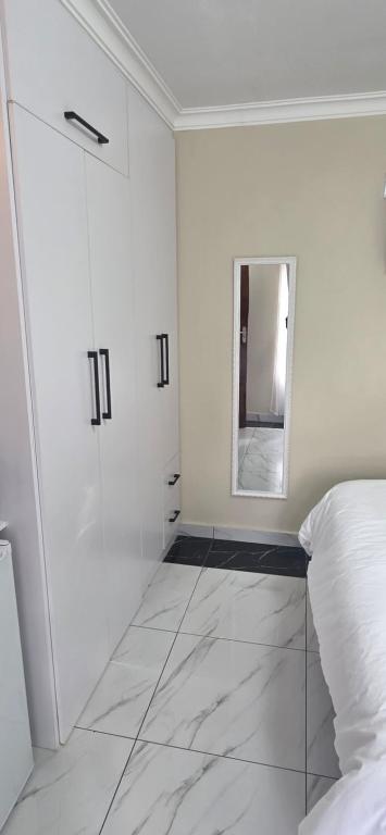Un dormitorio blanco con una cama y un espejo. en 28 Tambotie avenue, en Klerksdorp