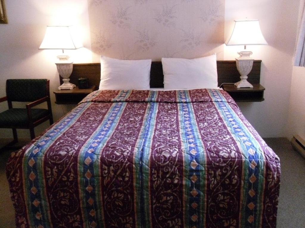 una camera d'albergo con un grande letto con due lampade di Canyon Alpine Motel a Boston Bar