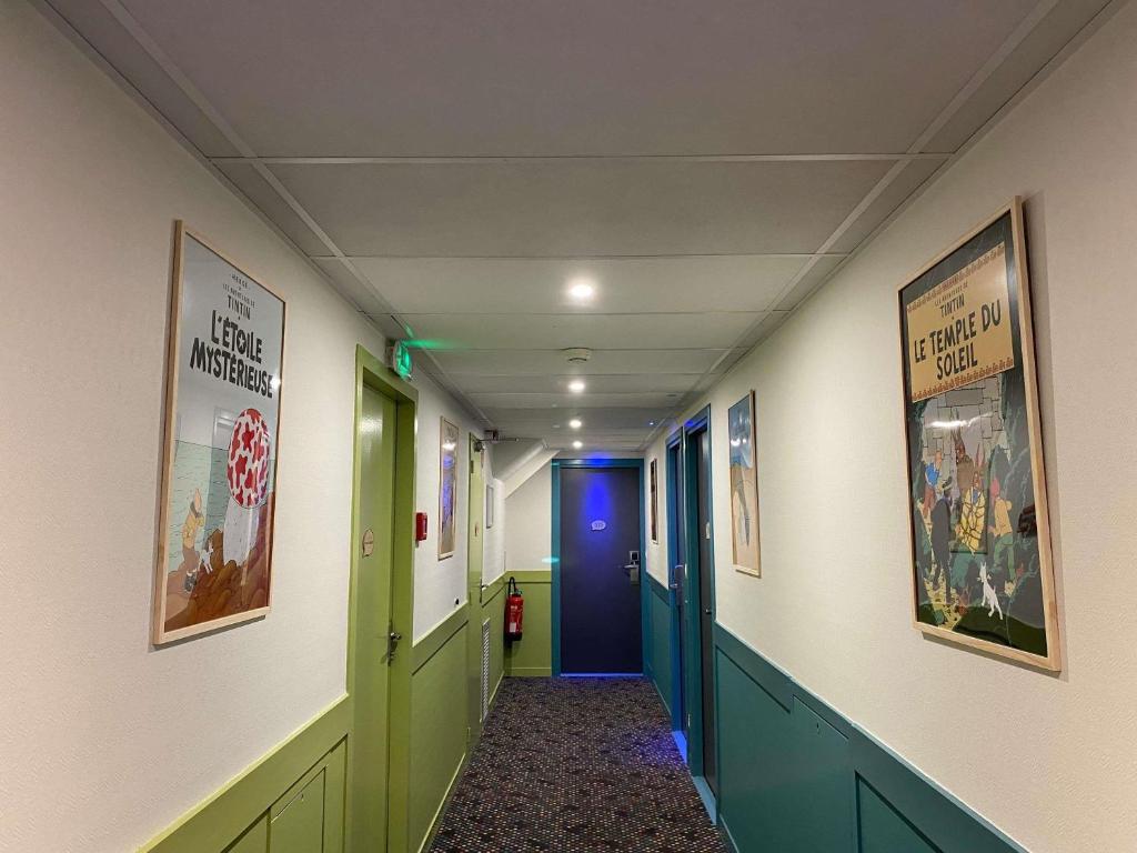 a hallway with green and blue doors and posters on the walls at ibis Styles Blois Centre Gare in Blois