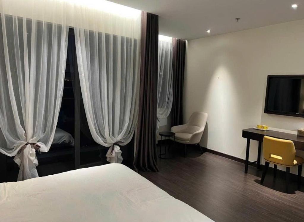 a bedroom with a bed and a desk and a television at Homestay Sapphire S2 cho thuê theo giờ 2 tiếng in Ha Long