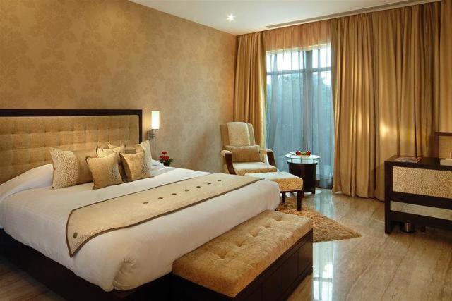 - une grande chambre avec un grand lit et une chaise dans l'établissement Royal Residence Cybercity - Gurugram, à Gurgaon