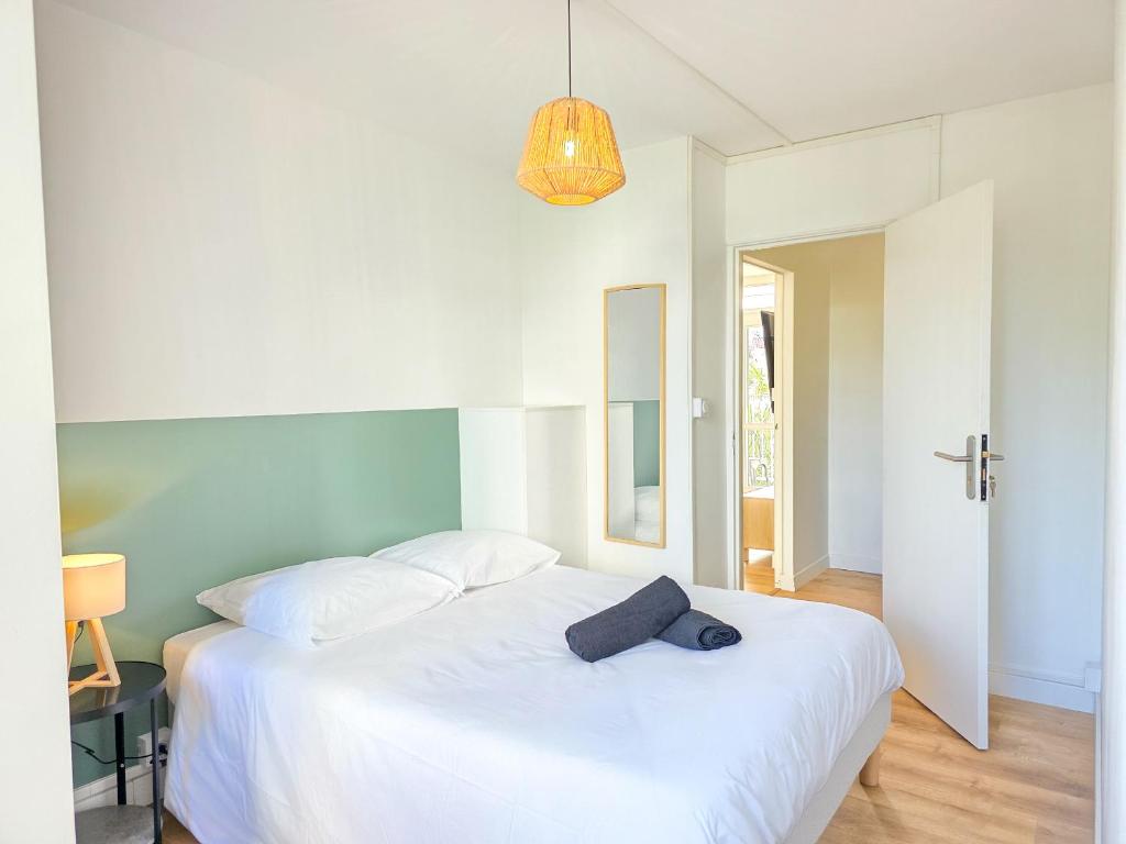 - une chambre avec un lit blanc et un chapeau dans l'établissement Le Lagon, Moderne, Parking & Proche du Centre, à Saint-Brieuc