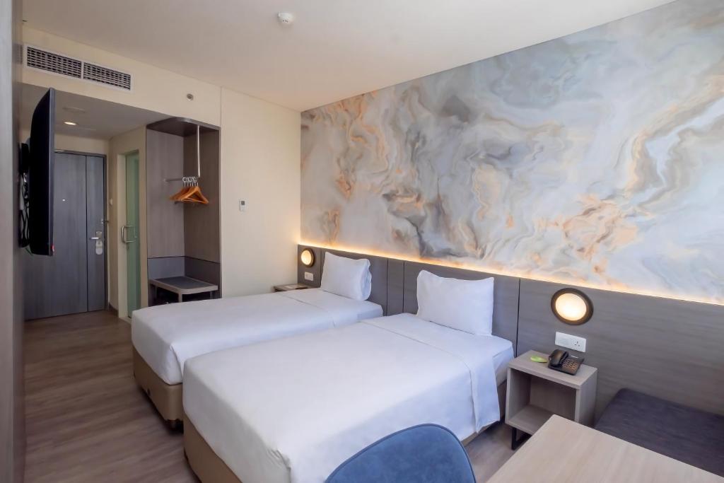 a hotel room with two beds and a painting on the wall at Zest Jemursari by Swiss-Belhotel International in Surabaya