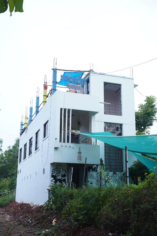 een wit gebouw met een blauwe luifel ervoor bij The Last Stop Backpackers Hostel in Auroville