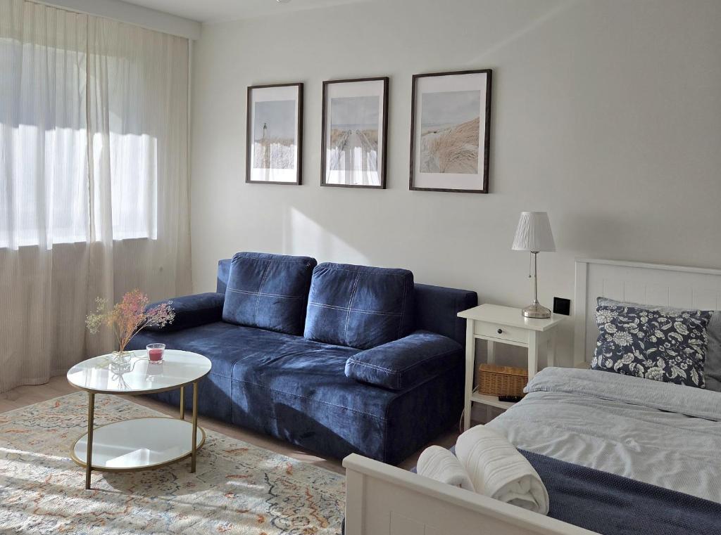 a living room with a blue couch and a bed at Morski Spokój Kołobrzeg apartment in Kołobrzeg