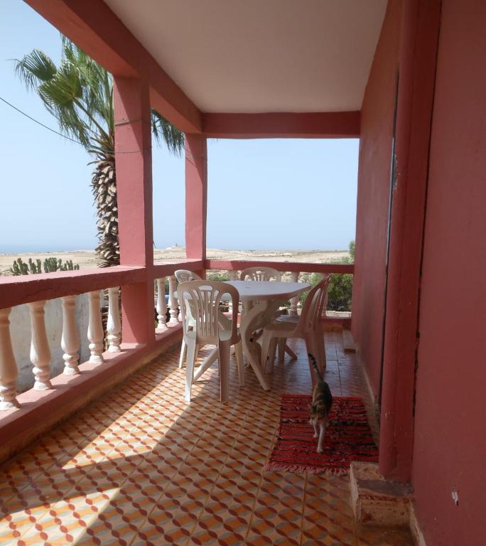 a cat standing on a balcony with a table and chairs at tasurft house imsoune in Imsouane