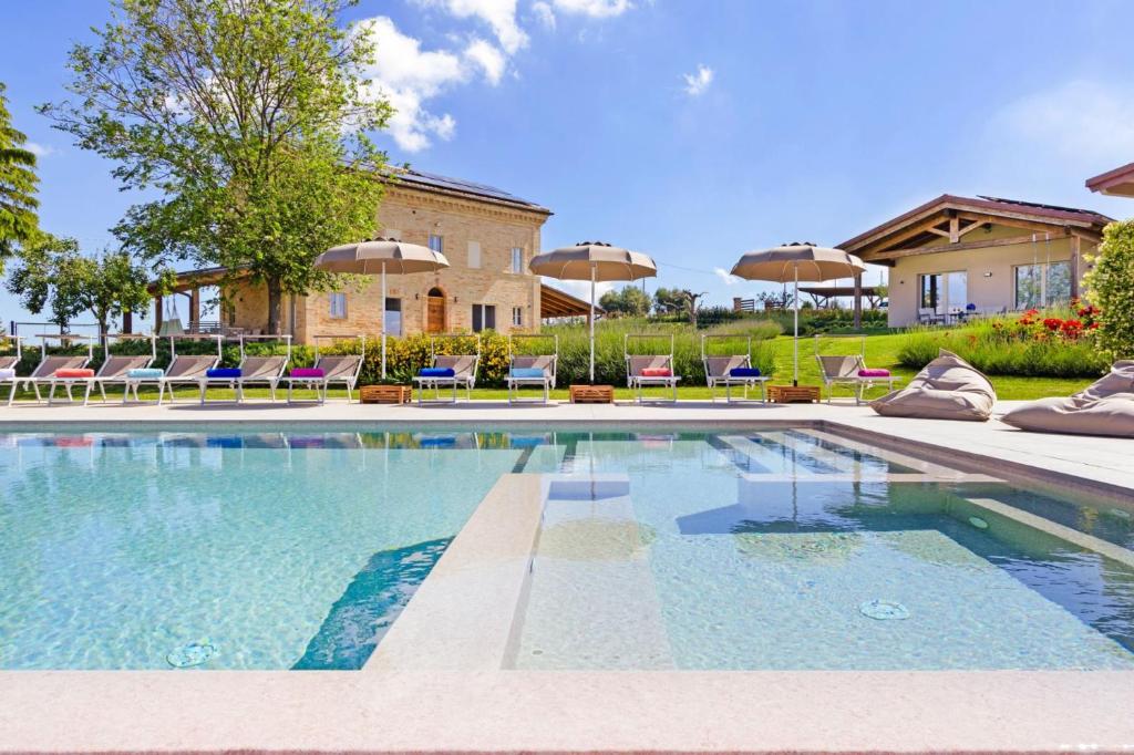 a swimming pool with chairs and umbrellas in front of a house at Villa Margherita in Francavilla dʼEte