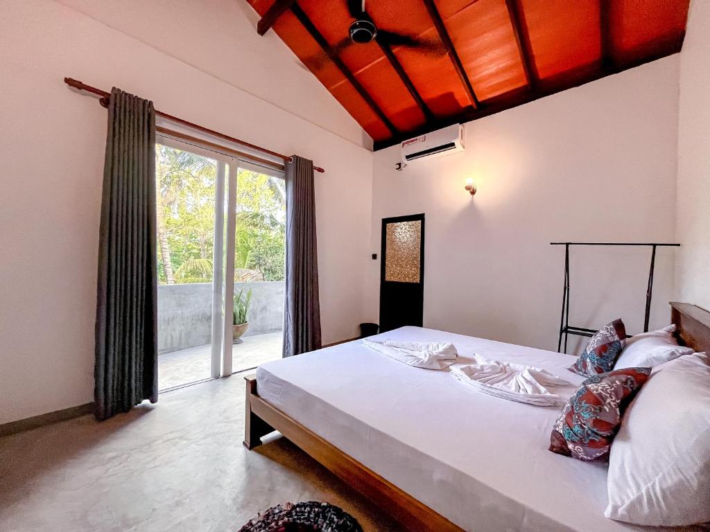une chambre avec un lit et une grande fenêtre dans l'établissement The Garden, à Ahangama
