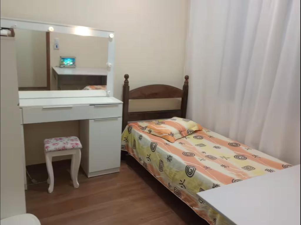 a small bedroom with a bed and a desk and a mirror at Casa 3 quartos na Estrada Real e Caminho de São Tiago in Ouro Branco