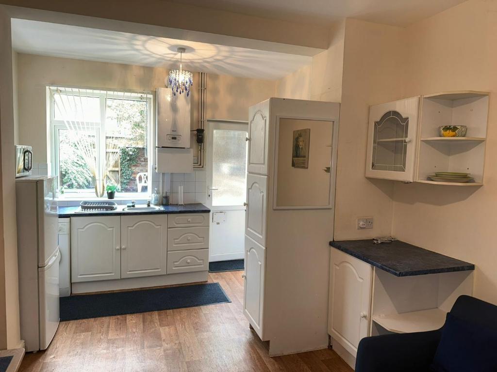 a kitchen with white cabinets and a window at Bentley View in Crewe