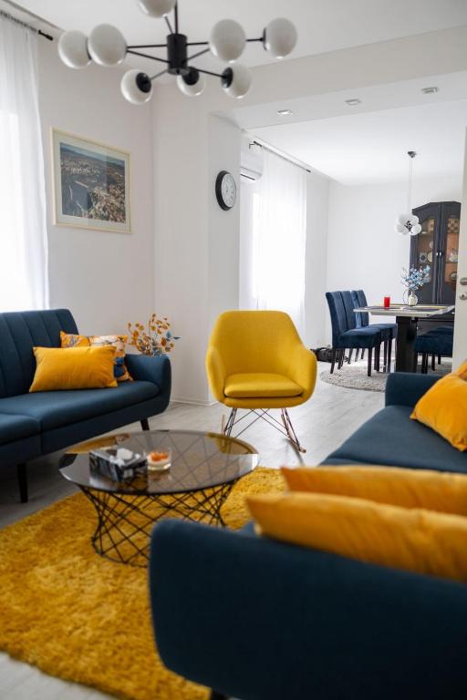 a living room with blue couches and a yellow chair at Una Riverside Heritage House in Bihać