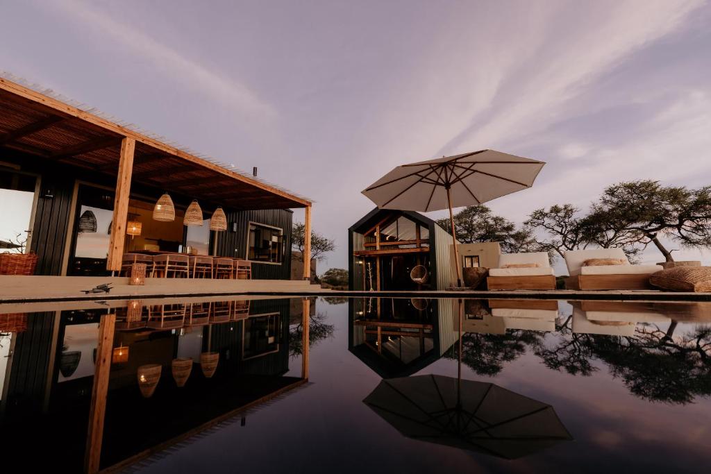 オチワロンゴにあるOtjiwa Savanna Luxury Villaのプールの隣に傘のある家