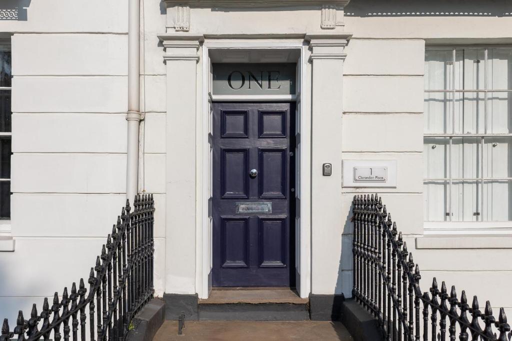 a blue door on a white building with a gate at Stylish 5-Bed Townhouse in Prime Leamington Spa in Leamington Spa