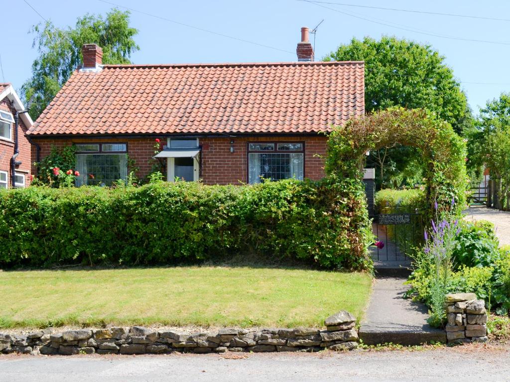 a brick house with a gate and a hedge at Peasholm in Thornton Dale