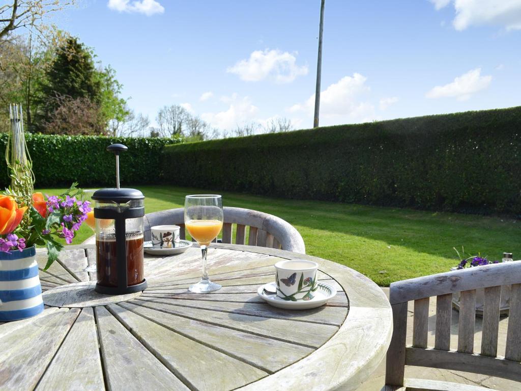 a wooden table with a glass of wine on it at Poplar Bungalow in Lyng