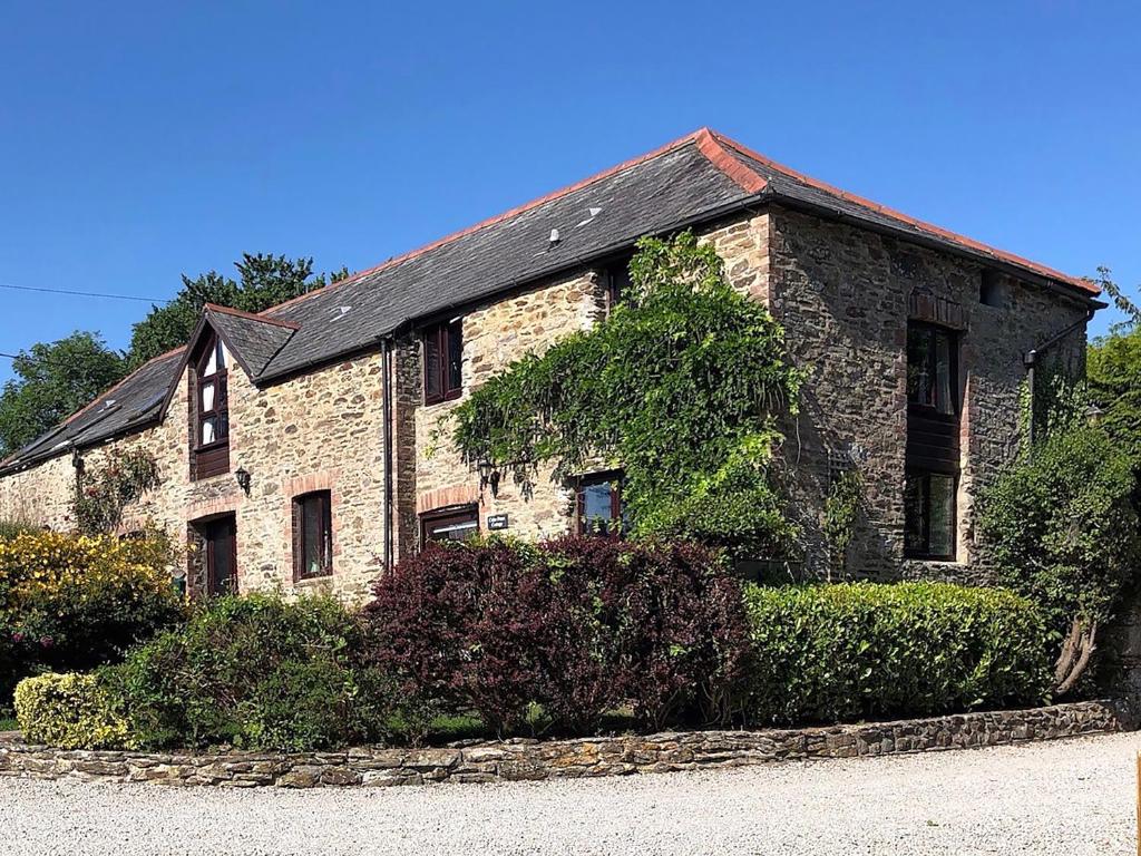 a stone house with a black roof on a street at Cider Press Cottage in Fowey