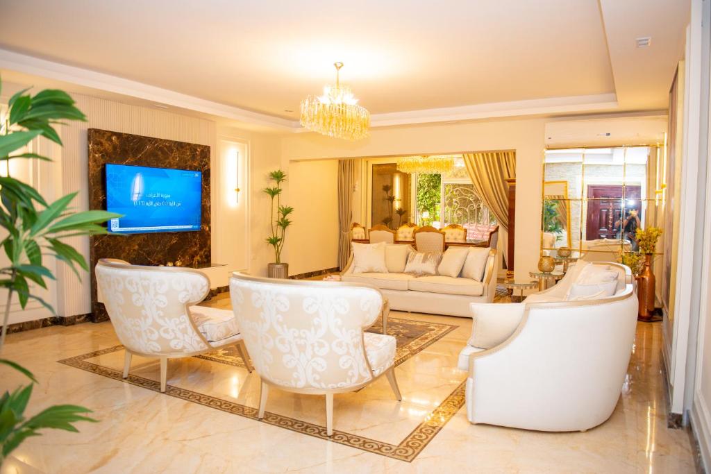 a living room with white furniture and a tv at Luxurious Family Apartment in Prime New Cairo with Garden in Cairo