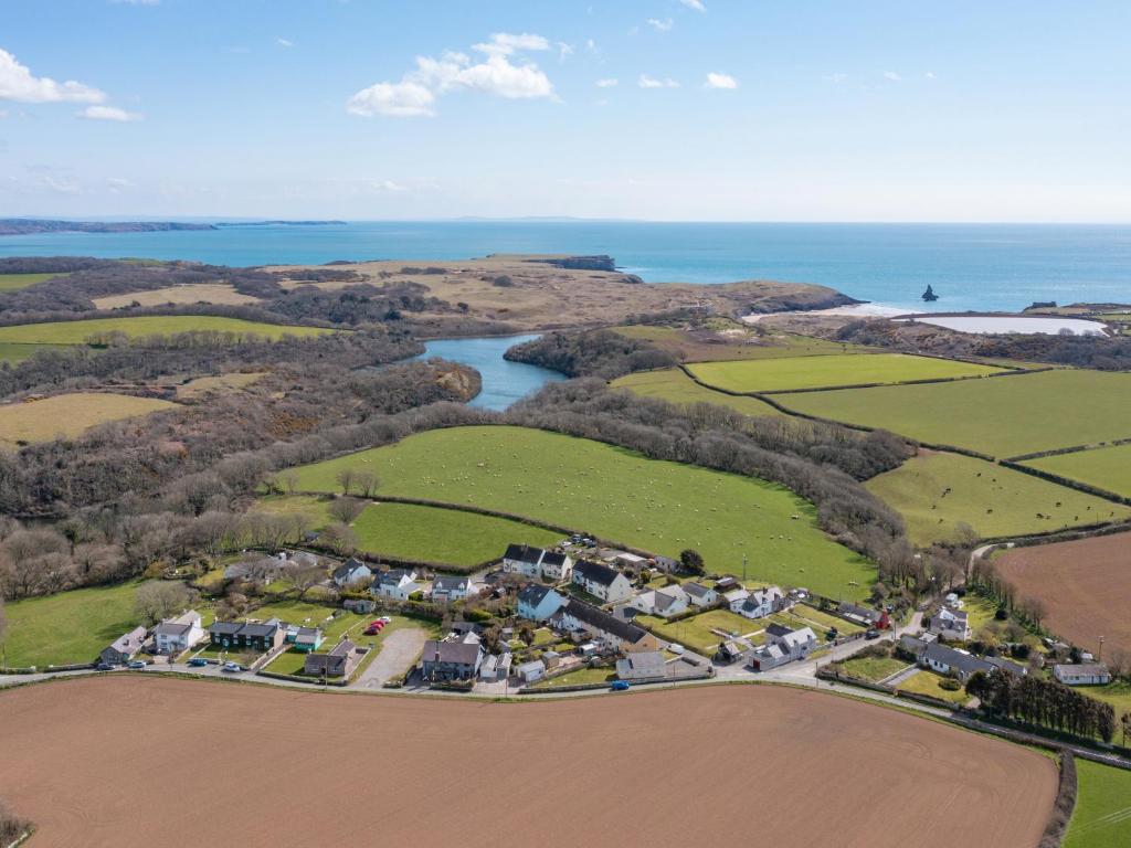 an aerial view of a village with a river and a field at Ash Tree Cottage in Bosherston