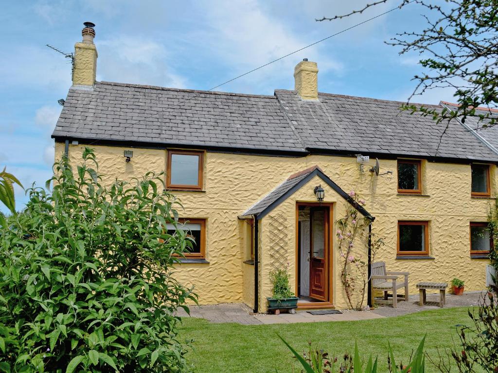 a yellow cottage with a bench in front of it at Dover Row Cottage in Zelah