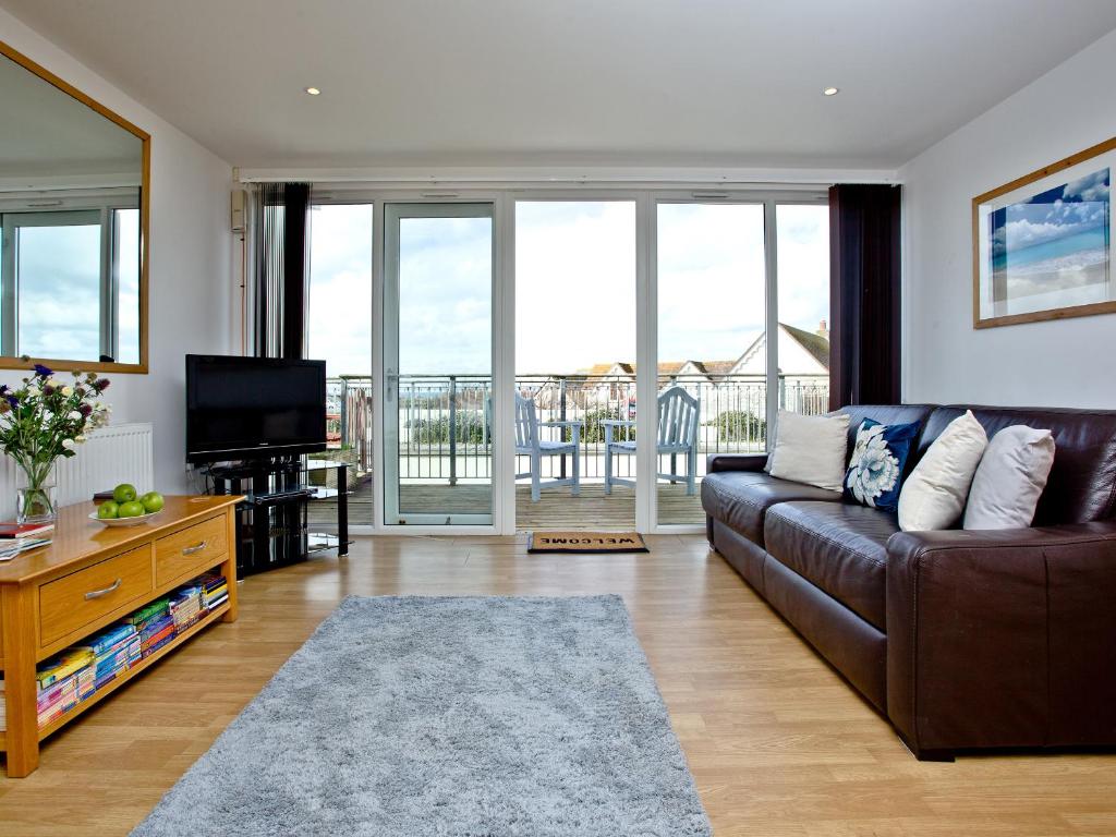 a living room with a brown couch and a television at Sea Glimpses in Saint Columb Minor
