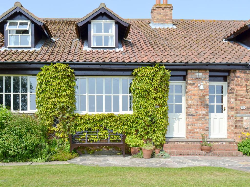a house with a bench in front of it at Rose Cottage - E1494 in Scalby