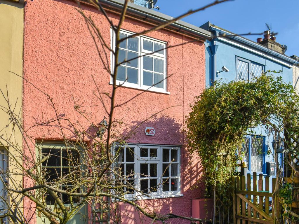 a pink brick house with a white window at Poppy Cottage in Halesworth