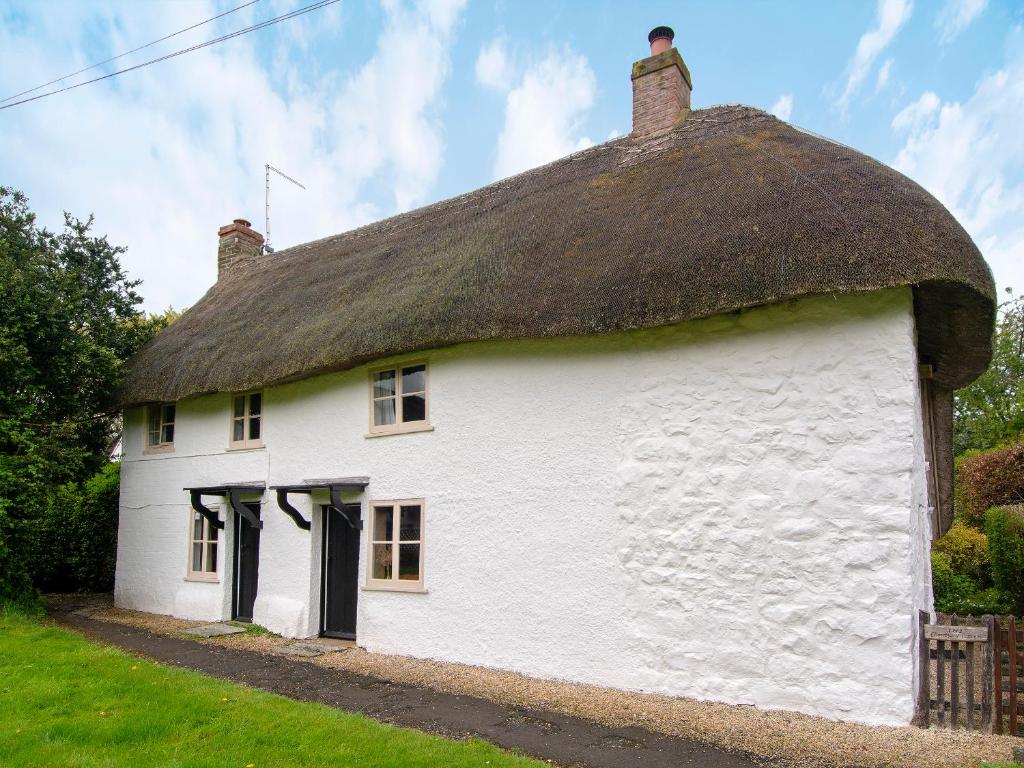 a white cottage with a thatched roof at Avebury Cottage in Avebury