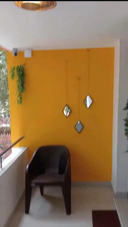 a chair in a room with a yellow wall at CHIC yellow 2bhk- Just 10 Mins to Beach and WhiteTown DAWN in Puducherry