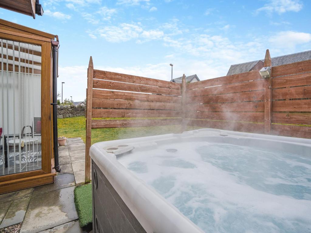 a hot tub in a backyard with a wooden fence at Clunnie Mor - S4615 in Aviemore