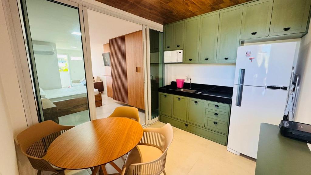 a kitchen with a wooden table and a refrigerator at Hoa Beach Flat 205 in Tamandaré