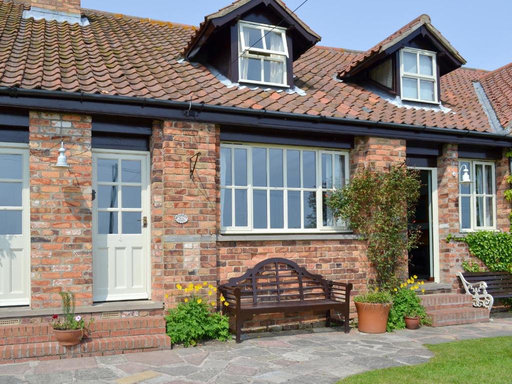 a brick house with a bench in front of it at Meadowsweet Cottage - E1496 in Scalby