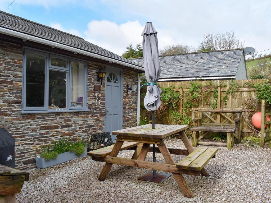 a picnic table with an umbrella next to a building at Garden Cottage - Uk30590 in Polperro