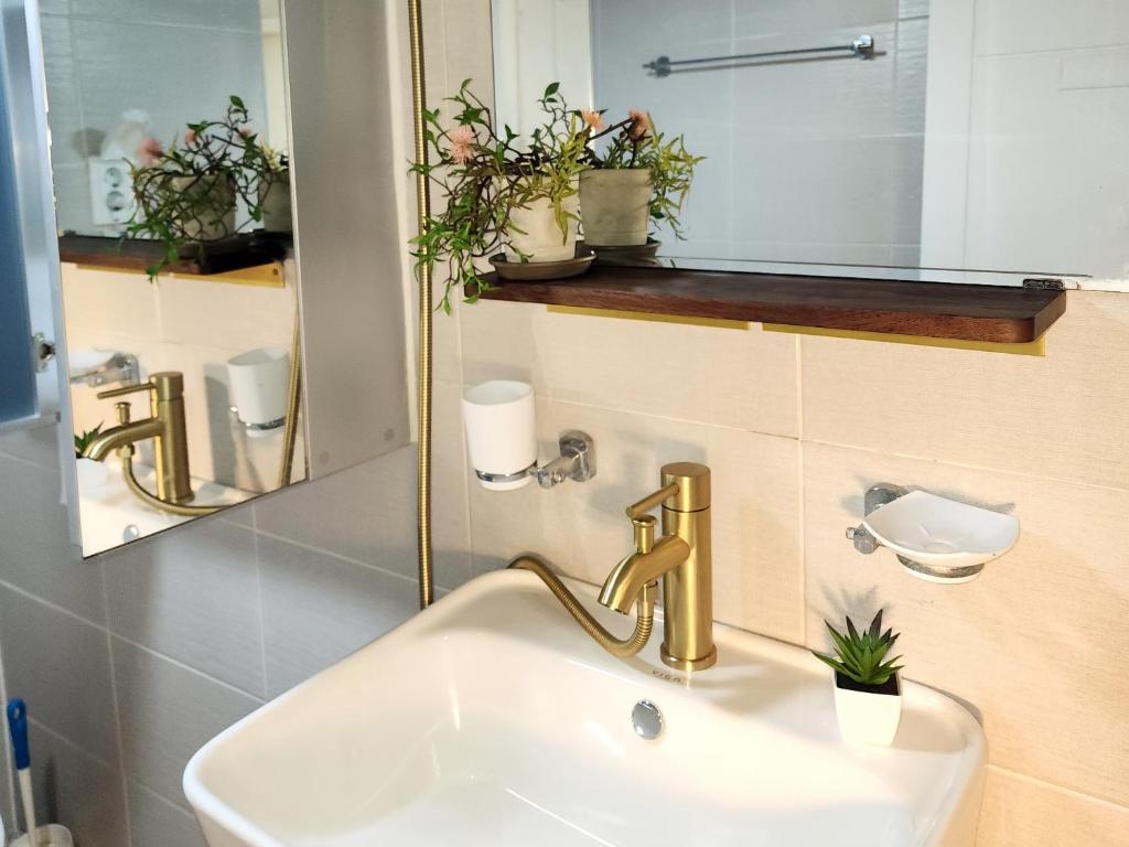 a bathroom sink with a gold faucet and a mirror at Lala Stay in Seoul