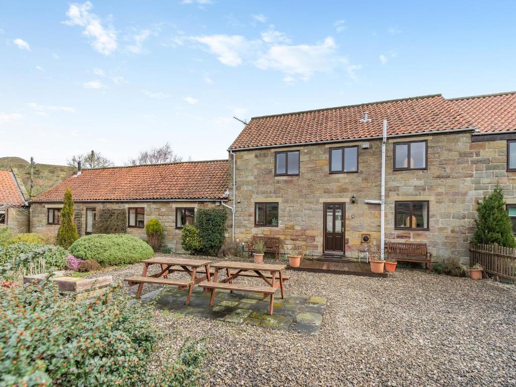 a house with two wooden benches in front of it at The Haybarn - Uk42935 in Rosedale Abbey