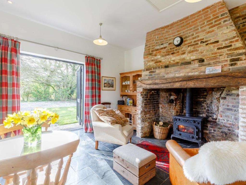 a living room with a fireplace and a brick wall at Pettingalls Farm Cottage in Great Ellingham