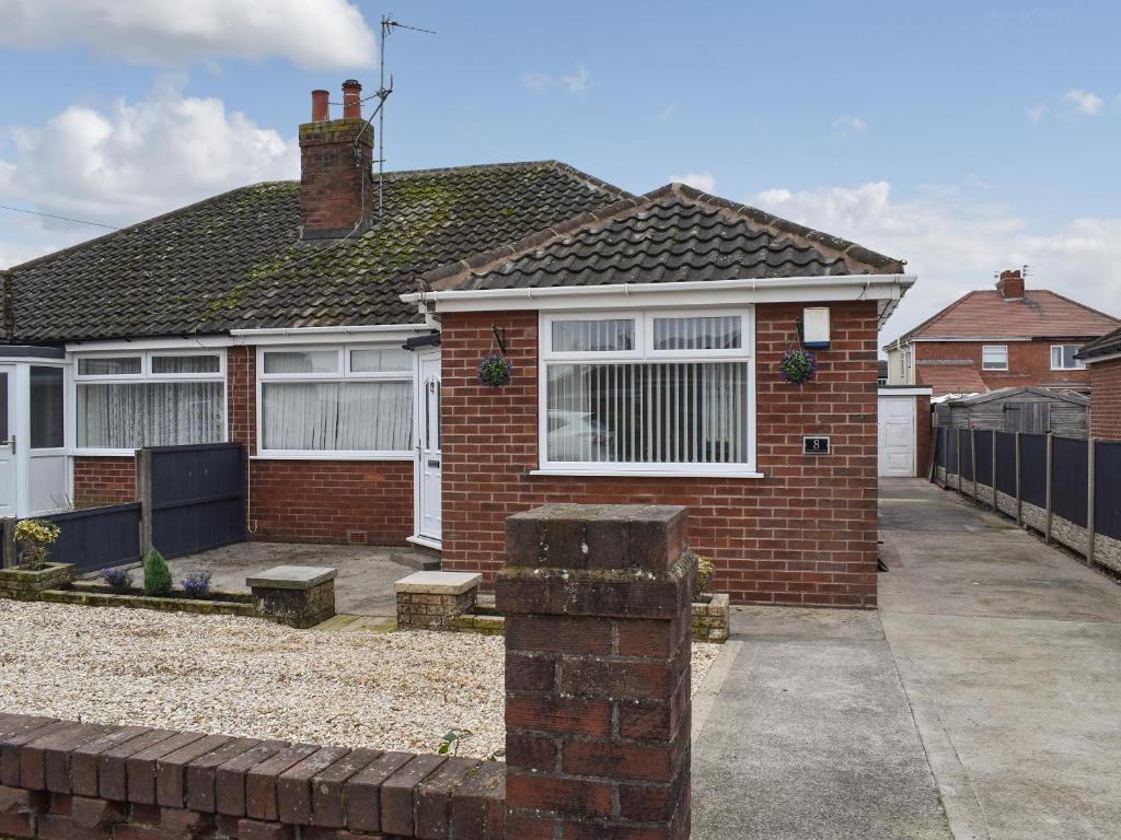 a red brick house with a fence and a driveway at Wharfdale Lodge in Thornton