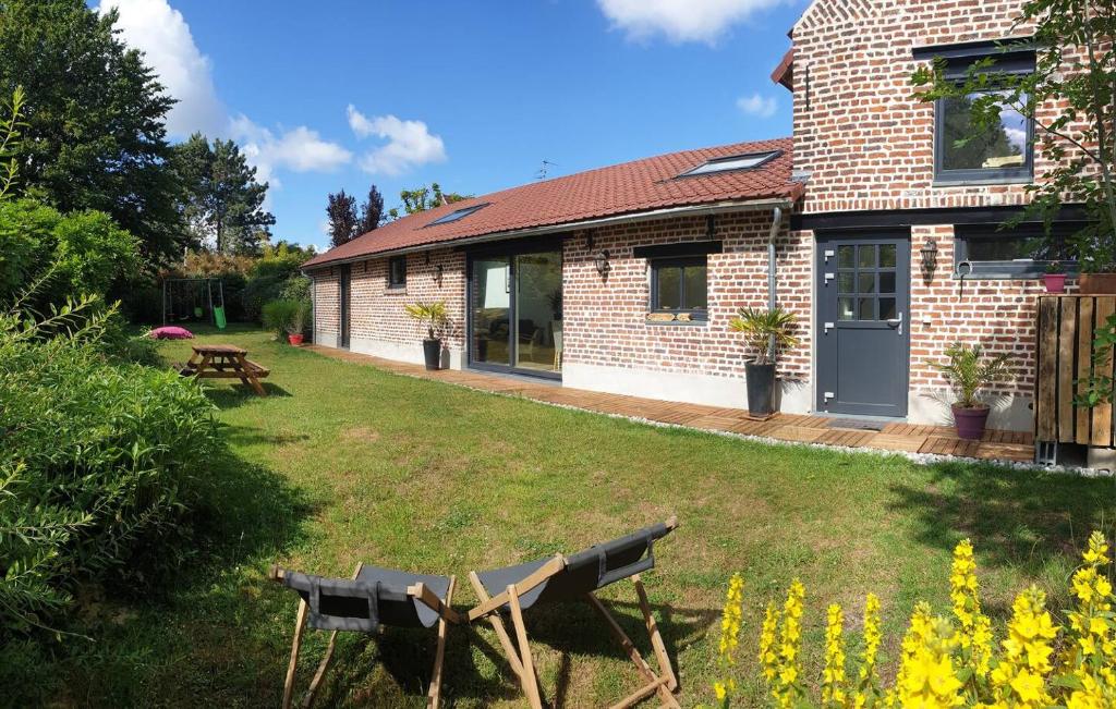 a brick house with a yard with a bench at La Jeannette Sainghin-en-Mélantois in Sainghin-en-Mélantois