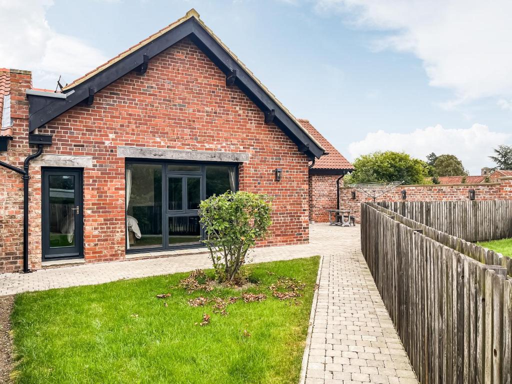 a brick house with a fence in front of it at Barn Owl Cottage - Uk48510 in Kirk Hammerton