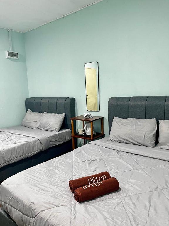 a hotel room with two beds with a pillow on the bed at Avina's Family Room in Setiu