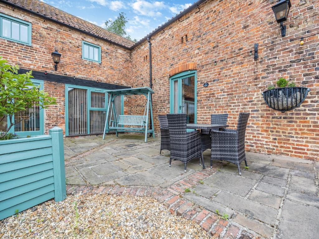 un patio con mesa y sillas frente a un edificio de ladrillo en The Granary - Uk44520, en North Thoresby