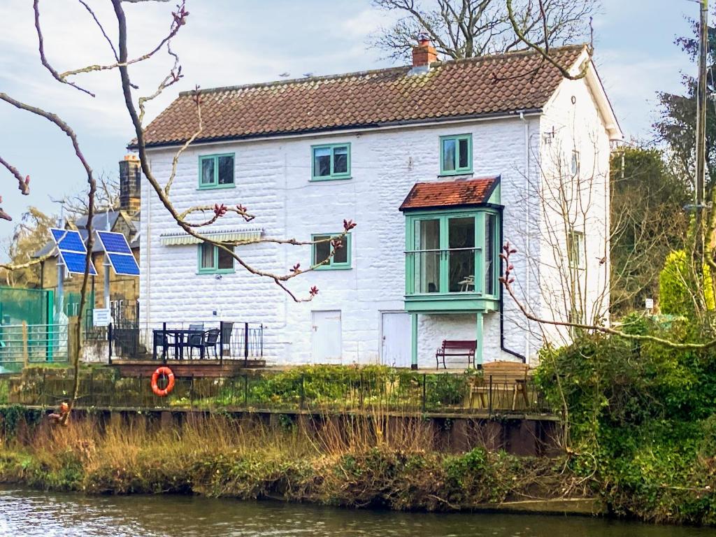 a white house sitting on the side of a river at Chainbridge Cottage in Whitby