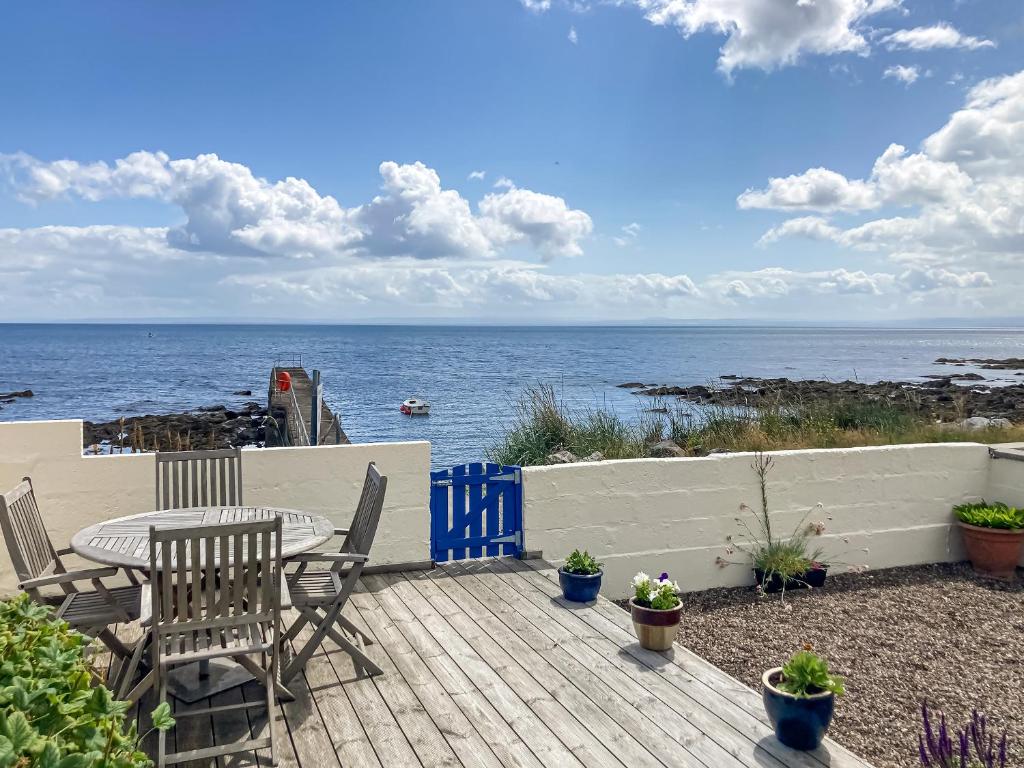eine Terrasse mit Tisch und Stühlen und dem Meer in der Unterkunft Cross Tides in Hilton of Cadboll