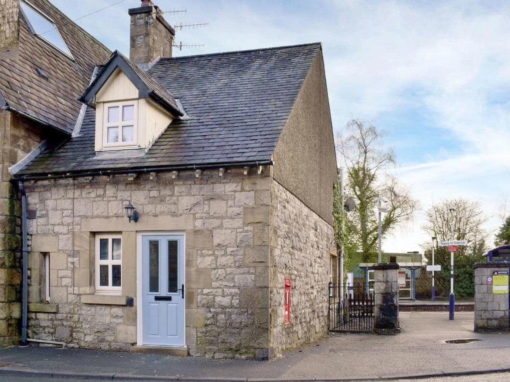 a small stone building with a white door at Station Cottage in Silverdale