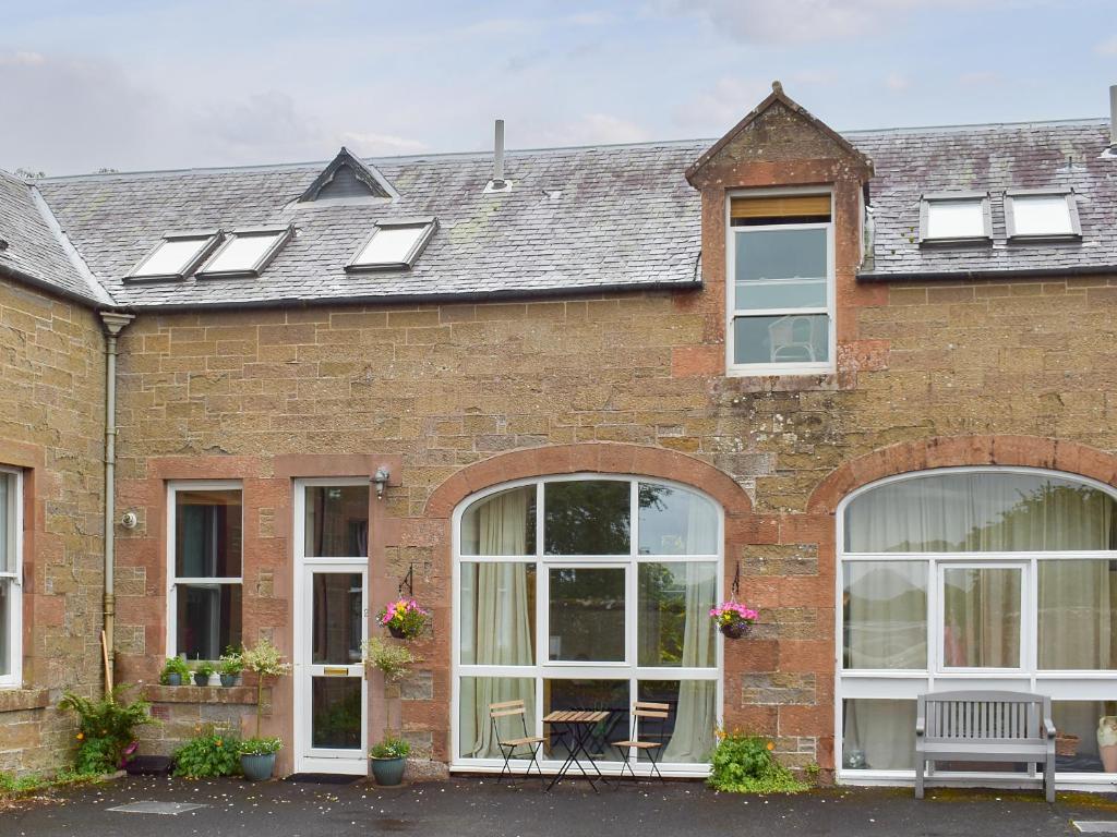 a brick house with white windows and a roof at Saddlers Cottage in Gattonside