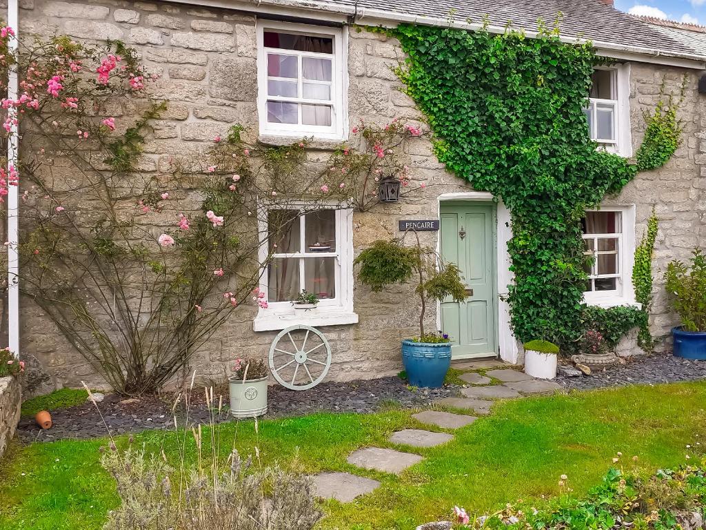 a stone house with a green door and ivy at Pencaire in Helston