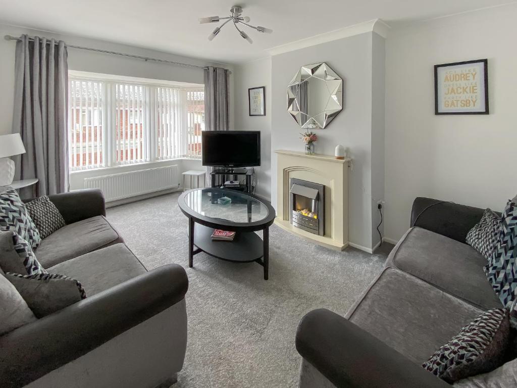 a living room with two couches and a fireplace at Coleridge Lodge in Thornton
