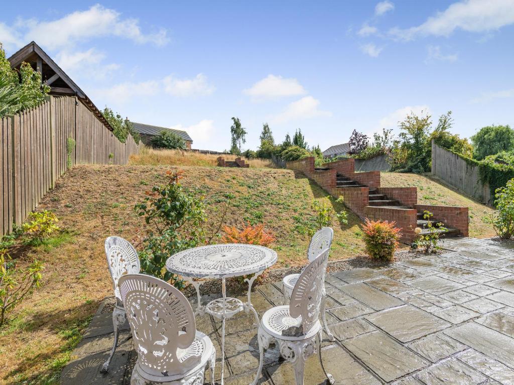 a patio with a table and chairs and stairs at Carey in Eastchurch