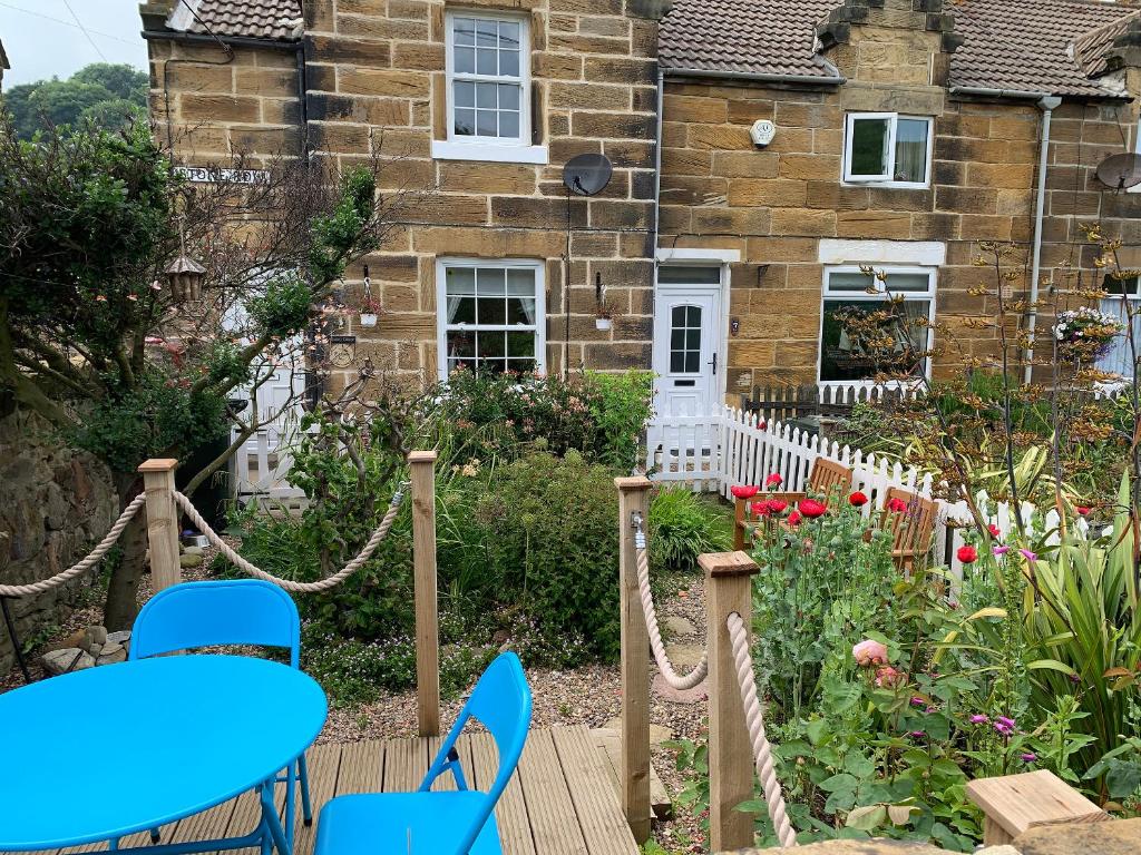 ein Haus mit einem blauen Tisch und Stühlen in einem Garten in der Unterkunft Quaker's Cottage in Carlin How